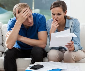 Stressed couple, surrounded by bills, feeling trapped in a job that barely pays the bills