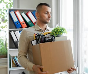 Man walking out of office with box, starting to apply lessons from getting fired