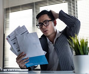 Person struggling with the psychology of debt while reviewing credit card statements