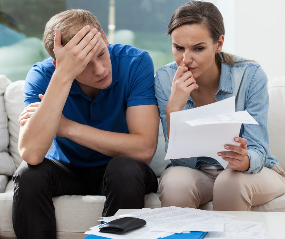 Stressed couple, surrounded by bills, feeling trapped in a job that barely pays the bills
