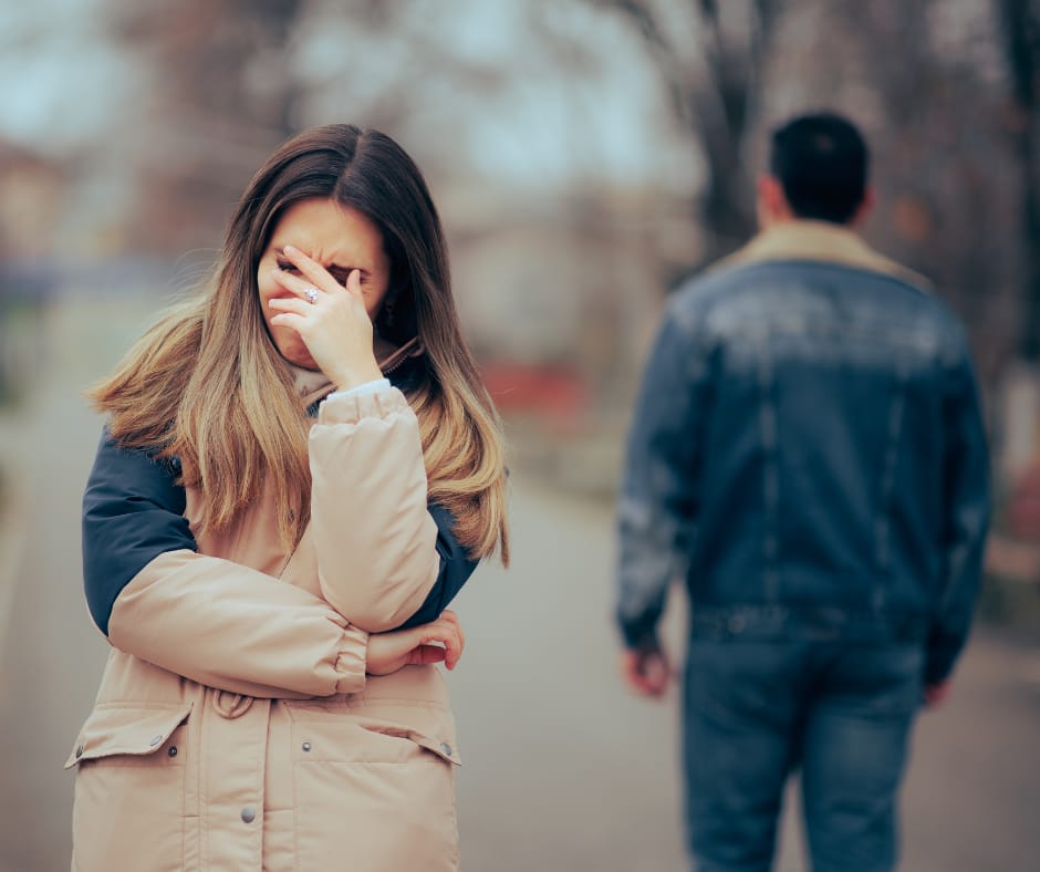 A woman cries after a breakup as her partner walks away, showing she’s not healed from past relationships and still carrying unhealed relationship trauma.