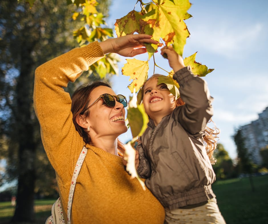 Single mom and daughter smiling outdoors under autumn leaves, showing How does single parenting affect a child through warmth, routine, and emotional security.